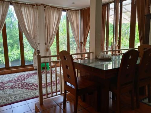 uma sala de jantar com mesa, cadeiras e janelas em Villa Gathering Yuni Syahla em Citaringgul 1
