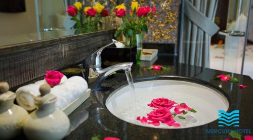 un lavabo con rosas rosas en el baño en Mercury Central Hotel Hanoi, en Hanói