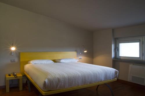 una camera da letto con un grande letto con lenzuola bianche e una finestra di San Lorenzo Si Alberga a Camigliatello Silano