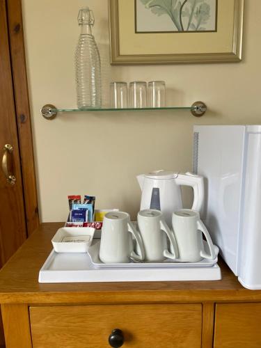 a tray with cups and coffee mugs on a counter next to a refrigerator at Sunset House B&B in Penrith