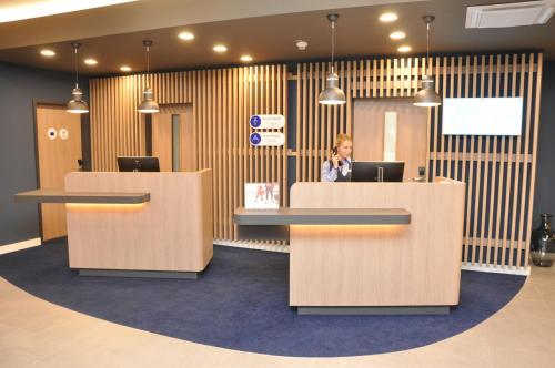 a woman talking on a phone in an office lobby at Holiday Inn Express - Sindelfingen by IHG in Sindelfingen