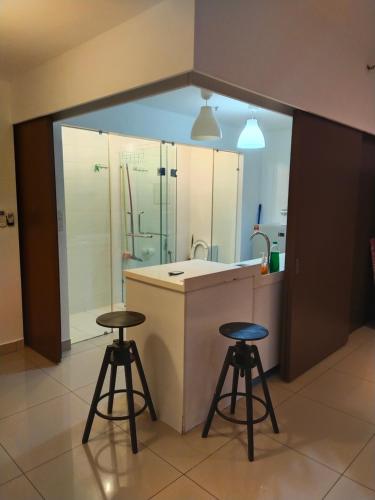 a kitchen with two stools and a sink and a shower at Trefoil in Setia Alam