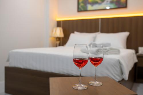 - deux verres de vin assis sur une table devant un lit dans l'établissement LILLY HOTEL, à Xã Thang Tam