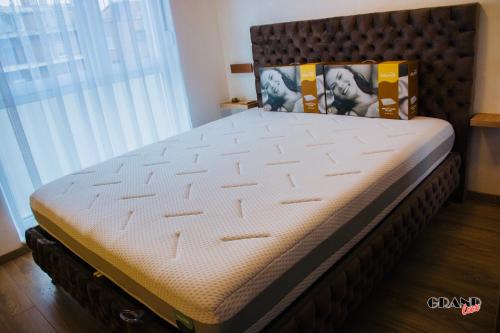 a bed in a bedroom with a large window at GRAND LUX Apartment in Doboj