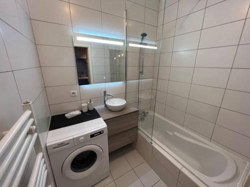 La salle de bains blanche est pourvue d'un lave-linge et d'une baignoire. dans l'établissement Esprit ALSACE: 70m2 de charme, à Mulhouse