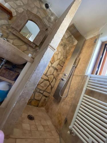 a bathroom with a shower with a stone wall at Villa Nirya - Trulli Resort & Pool by TrulloVista in Martina Franca
