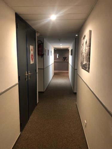 an empty hallway with a hallway leading to a room at Hôtel Le Relais in Fleurance