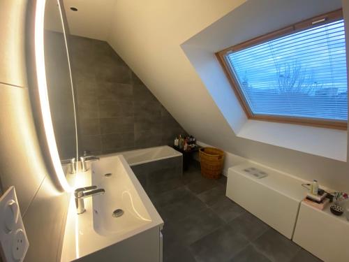 a bathroom with a sink and a tub and a window at Chambre chez Marjorie in Brest