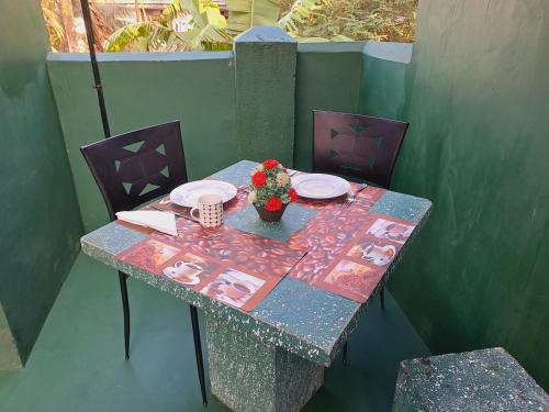 a table with plates and a vase of flowers on it at 'Franklyn', Homestay in Kalutara