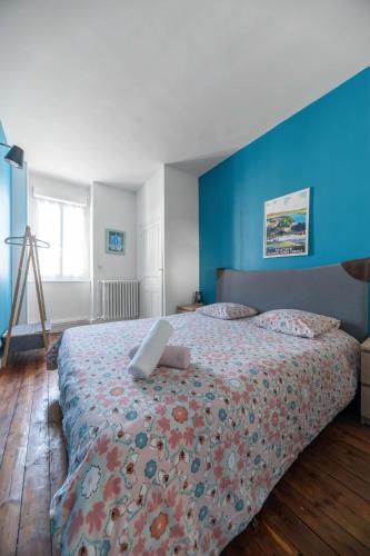 une chambre avec un grand lit avec un mur bleu dans l'établissement Le 482 - Grand Appartement design & Confort - 4 chambres, à Vichy