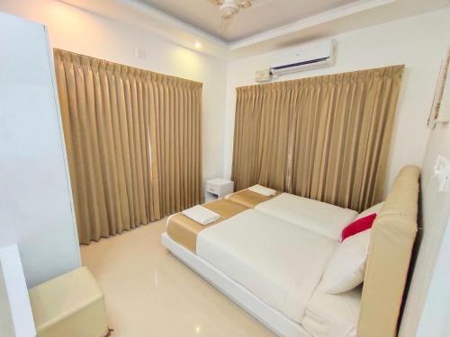 a bedroom with a large white bed and a couch at Le Villagio Resort & Domes in Sultan Bathery