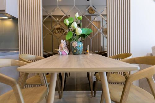 a dining room table with a vase of flowers on it at The Song Luxury Condotel Vung Tau - Căn hộ cao cấp Luca's House in Vung Tau