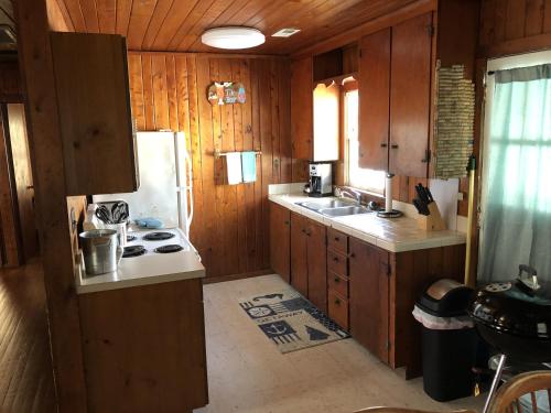 a kitchen with wooden cabinets and a white refrigerator at BlackBeard's Retreat - Historic and Pet Friendly cottage in Kitty Hawk