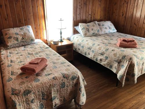 two beds in a room with wooden walls and wooden floors at BlackBeard's Retreat - Historic and Pet Friendly cottage in Kitty Hawk