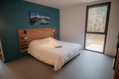 a bedroom with a bed with a wooden headboard and a window at L'Orée des Sources in Volvic