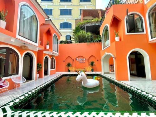 an orange building with a pool with a fake unicorn in it at L'abri Retreat in Vĩnh Phúc