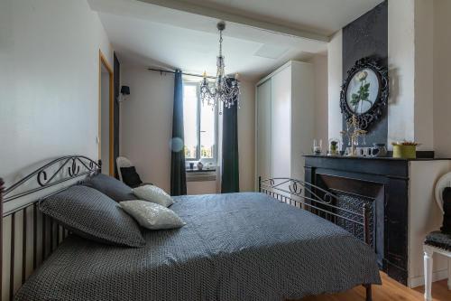 1 dormitorio con 1 cama con chimenea y lámpara de araña en Le Mas Rose en Villeneuve-lès-Montréal