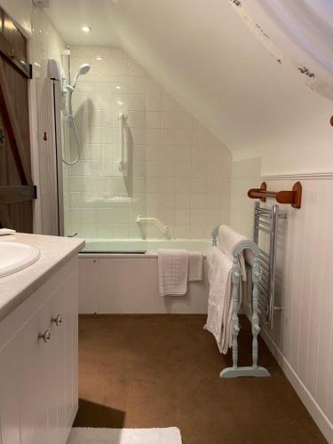 a bathroom with a bath tub and a sink at Apple Blossom Cottage - Spring Cottages, Cheddar in Cheddar