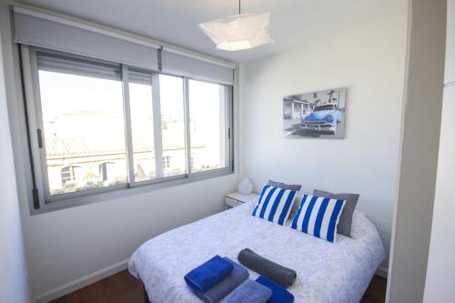 een slaapkamer met een bed met blauwe kussens en een raam bij Apartment Livemálaga Victoria in Málaga