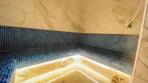 バニャ・ルカにあるWellness&Spa Hotel Astoryaのバスルーム(ブルータイルの壁のバスタブ付)