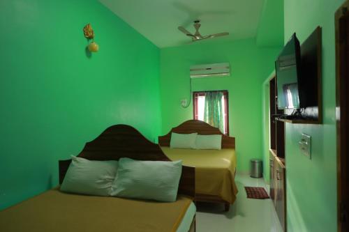 a green room with two beds and a television at Farmdean Resort in Kanyakumari
