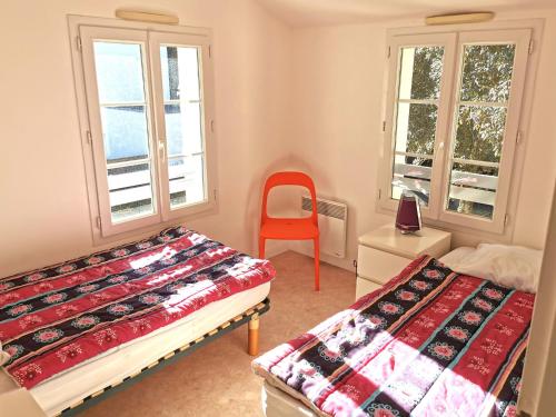 een slaapkamer met 2 bedden en een rode stoel bij LA LEGERE - 500m de la Mer in Jard-sur-Mer