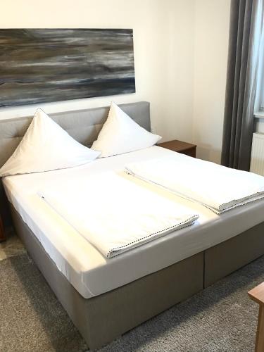 a bed with white sheets and pillows on it at Lüttje Huus Frieda mit Strandkorb am Strand von Mai bis September in Cuxhaven