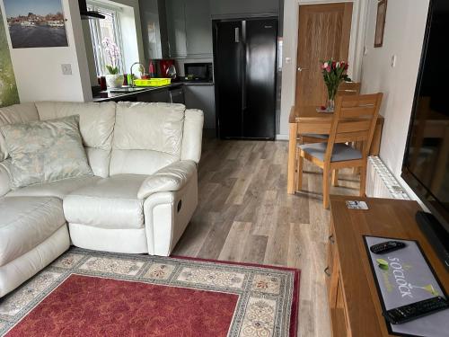 a living room with a white couch and a kitchen at 5 O Clock Somewhere with Private Hot Tub in Sheringham