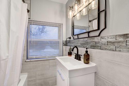 a white bathroom with a sink and a mirror at Luxurious Detroit Home - Walk to Golf and Park! in Detroit