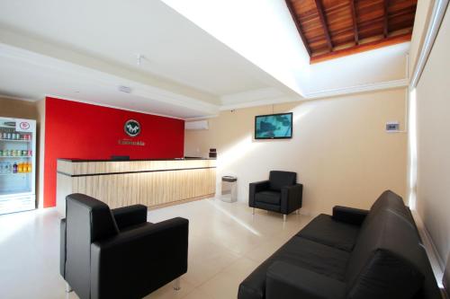 a waiting room with two black chairs and a red wall at Pousada Esmeralda Olímpia in Olímpia