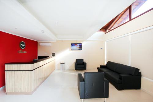 a lobby with a black couch and a red wall at Pousada Esmeralda Olímpia in Olímpia