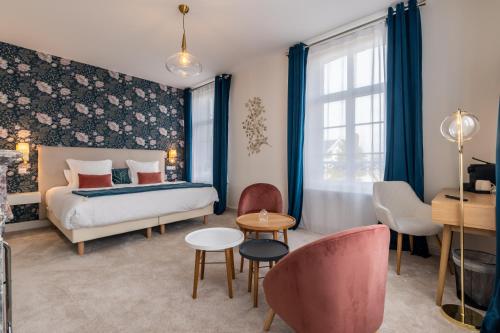 een slaapkamer met een bed en een tafel en stoelen bij Hôtel Échappée en Baie - Parking privé gratuit dont forfaits bornes électriques réservable in Saint-Valery-sur-Somme