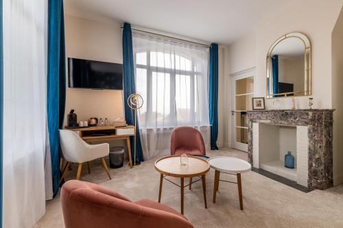 a living room with a fireplace and blue curtains at Hôtel Échappée en Baie - Parking privé gratuit dont forfaits bornes électriques réservable in Saint-Valéry-sur-Somme