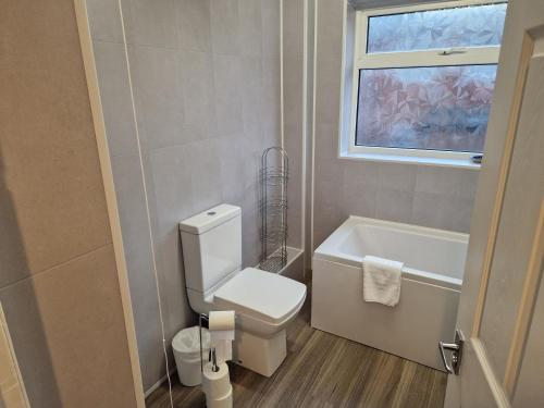 a bathroom with a toilet and a tub and a window at Grange Villa Amethyst 3 Bed House near Chester le Street, sleeps 6 Guests in Chester-le-Street