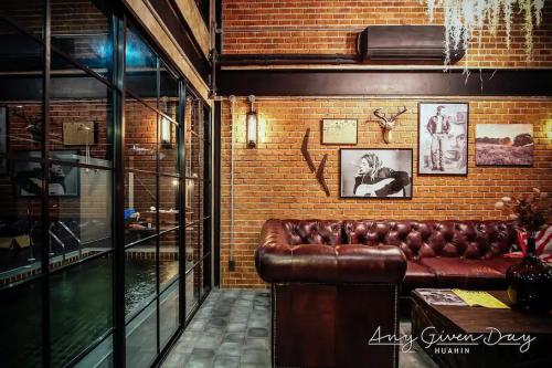 a leather couch in a room with a brick wall at Any Day House Huahin in Hua Hin