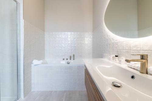 a white bathroom with a tub and a sink at Hôtel Échappée en Baie - Parking privé gratuit dont forfaits bornes électriques réservable in Saint-Valery-sur-Somme