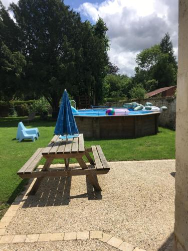 a picnic table with a blue umbrella next to a pool at La petite Brainoise - Gîte avec salle jacuzzi 120 jets in Braine