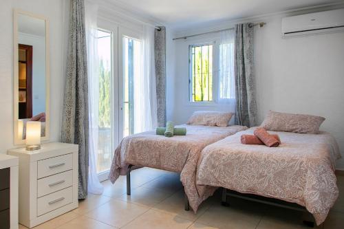 1 dormitorio con 2 camas y ventana en Villa Armonía, en Benitachell