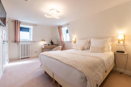a white bedroom with a large bed with white pillows at Hôtel Échappée en Baie - Parking privé gratuit dont forfaits bornes électriques réservable in Saint-Valery-sur-Somme
