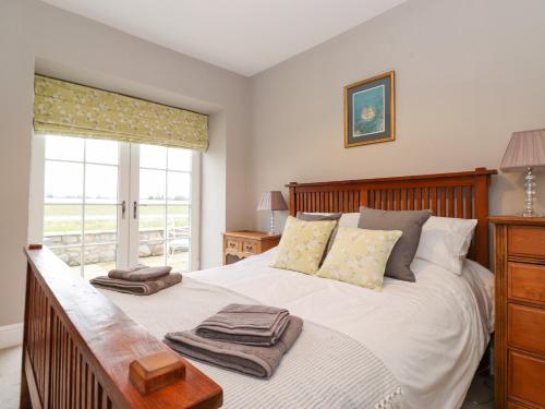 a bedroom with a large white bed with a window at Farnelea in Chathill