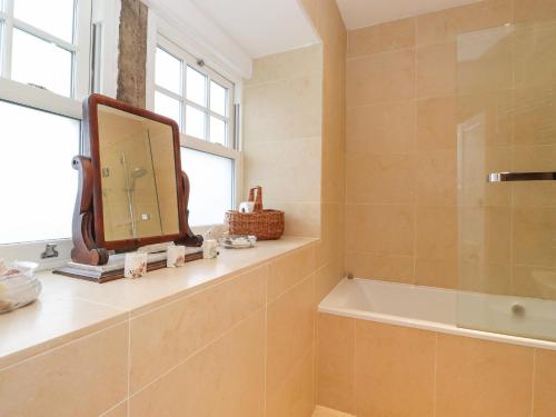 a bathroom with a mirror and a bath tub at Farnelea in Chathill