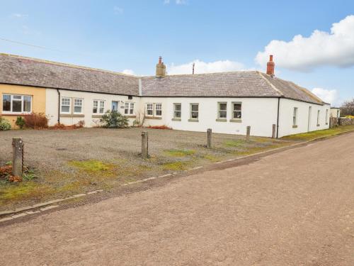 an empty road in front of a white house at Farnelea in Chathill