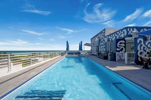 ein Schwimmbad mit dem Ozean im Hintergrund in der Unterkunft Ocean Drive Apartments with Rooftop Pool, South Beach, Miami in Miami Beach