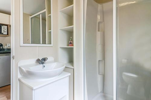 a white bathroom with a sink and a shower at Beachside caravan in Mablethorpe