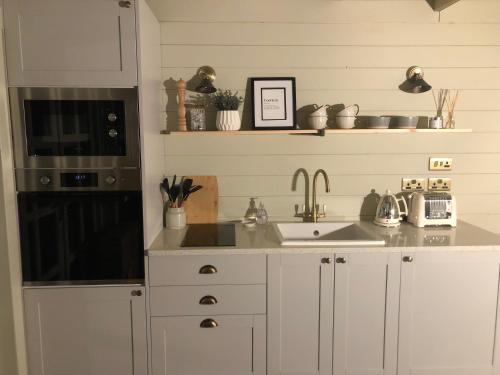 una cocina con armarios blancos y fregadero en Highland cabin - relaxing hot tub, en Inverness