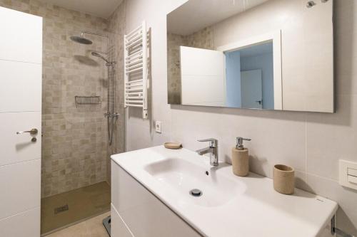 y baño blanco con lavabo y ducha. en MyHouseSpain - Piso en centro Gijón a pocos minutos de las playas en Gijón