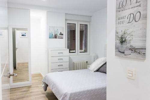 a white bedroom with a bed and a window at MyHouseSpain - Piso en centro Gijón a pocos minutos de las playas in Gijón