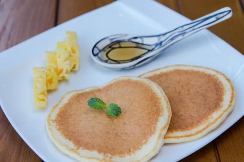 a white plate with two pancakes and pasta on it at Aviary Hanoi Hotel & Travel in Hanoi