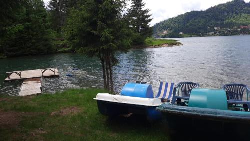 a group of chairs and a boat on a lake at Cabana Busuioc in Colibiţa