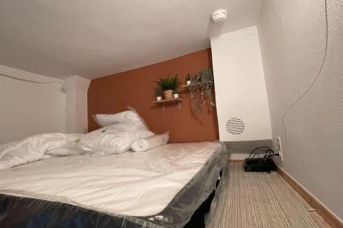 um pequeno quarto com uma cama com lençóis brancos em Charmant cocon au cœur de Dijon em Dijon